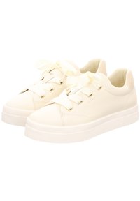 White sneakers made of smooth synthetic material with a rounded toe, flat sole, and decorative ribbon laces. Features a logo on the side.