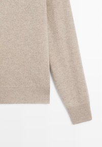 Maglione beige realizzato in morbido materiale lavorato a maglia, con scollo rotondo, maniche lunghe con polsini e orlo finemente rifinito senza motivi.