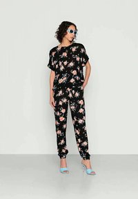 Conjunto de dois peças com padrão floral preto, incluindo uma blusa de manga curta e calças ajustadas. Apresenta flores em tons de rosa e branco, tecido leve e punhos canelados.