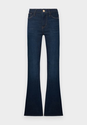 Jean évasé bleu foncé en denim, doté d'une taille haute, de cinq poches et de coutures dorées. Les bas sont larges et légèrement effilochés.