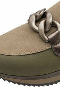 Olive green shoe with a textured suede upper and a prominent metallic chain accent. Features a thick sole with tread and stitched detailing.