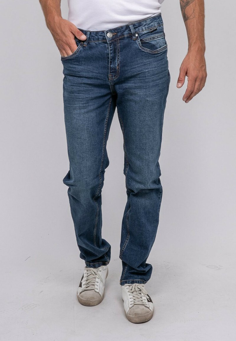 Jeans en denim bleu foncé avec une coupe droite, présentant des poches avant, des détails de couture subtils et une finition légèrement délavée.