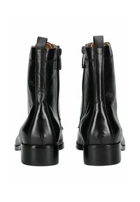 Botas de cuero negro hasta el tobillo con una textura suave, cremalleras laterales, puntera redondeada y un tacón ancho bajo. Las costuras añaden detalle al diseño.