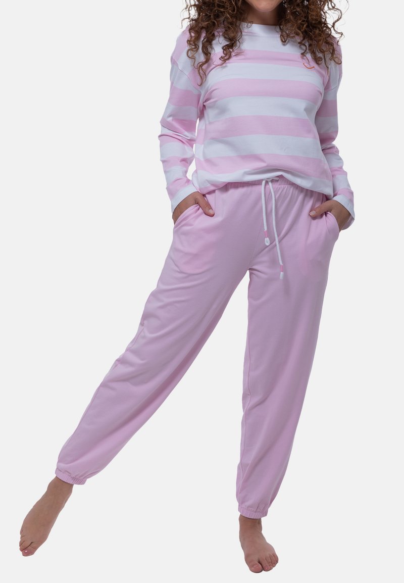 Camicia a maniche lunghe a righe rosa chiaro, abbinata a pantaloni jogger rosa chiaro con coulisse. Il tessuto sembra morbido; i polsini e i pantaloni sono arricciati.