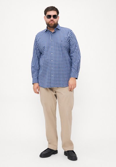 Μπλε και λευκή καρό πουκαμίσα με μακριά μανίκια, μπεζ παντελόνι και μαύρα παπούτσια. Το μοντέλο φοράει γυαλιά ηλίου και στέκεται μπροστά σε απλό φόντο.