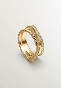 Conjunto de anillos de oro que presenta tres bandas: una lisa, otra texturizada con pequeñas protuberancias y una tercera adornada con piedras transparentes incrustadas.