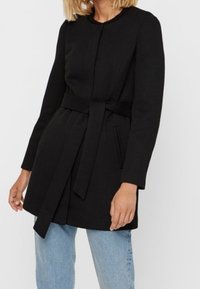 Black coat with a belted waist, long sleeves, and a round neckline. Features two front pockets and a straight cut.