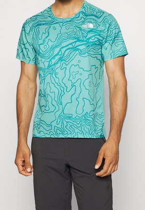 Homme portant un t-shirt turquoise à manches courtes avec un motif de carte topographique bleu foncé et un petit logo blanc The North Face sur la poitrine.