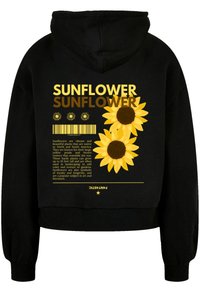 Black cropped hoodie featuring a sunflower graphic in yellow with a brown center. Text includes information about sunflowers and design elements.