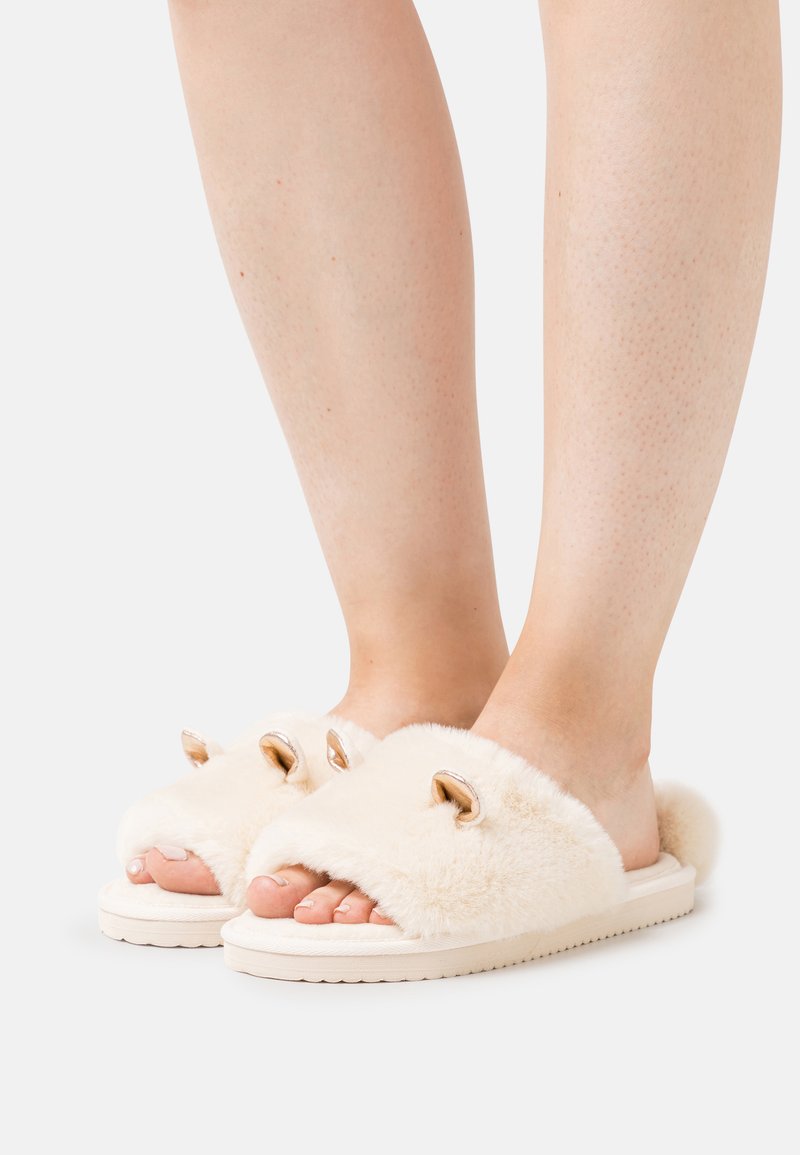 Faux fur slide slippers in off-white with open toe. Features gold-tone hardware and plush texture, mounted on a durable white sole.