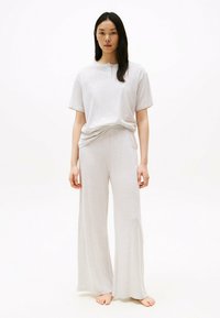 Lys grå loungewear sæt med en kortærmet skjorte og vide bukser, lavet af blødt stof. Enkel design, afslappet pasform.