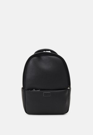 Un sac à dos en cuir noir lisse avec une poignée supérieure et une poche zippée à l'avant, présenté sur un fond blanc uni.