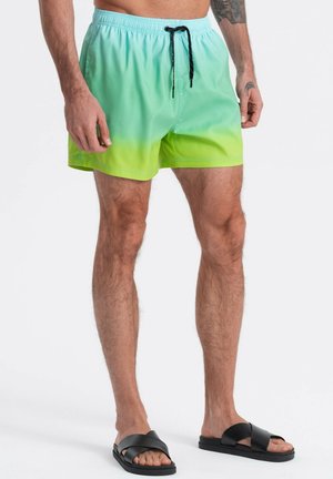 Badehosen in einem Farbverlauf von Türkis zu Grün, mit einem elastischen Bund, verstellbarem Kordelzug und einer glatten Textur. Schwarze Sandalen sind enthalten.