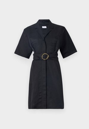 Vestido negro de camisa con mangas cortas, bolsillos delanteros, cintura ceñida con un anillo retorcido en tono dorado y diseño de botones.