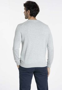 Pull en tricot gris avec des manches longues, des poignets et un ourlet côtelés. Doté d'un col rond classique et d'une texture lisse avec des détails de design minimaux.