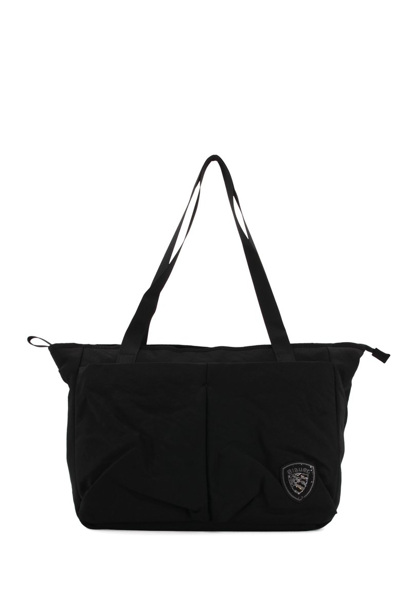 Sort tote bag lavet af blødt stof, med to håndtag, to frontlommer og et dekorativt skjold-logo på siden.