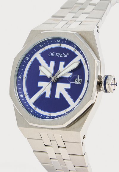 Montre-bracelet en métal argenté avec cadran bleu, motif flèche blanche, affichage de la date à 3 heures et logo "Off-White" sous 12 heures.