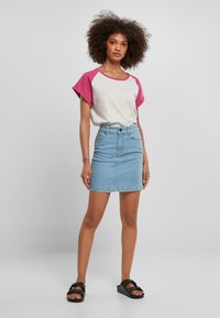 Grå og rosa kortermet skjorte med rund hals, kombinert med en lyseblå denimskjørt. Enkelt design og avslappet passform. Flate svarte sandaler.