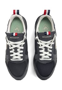Zapatillas de malla negra y ante con cordones blancos, plantilla verde y detalle en la pestaña del talón en rojo, blanco y azul. Logo "ROSSIGNOL" en la lengüeta.
