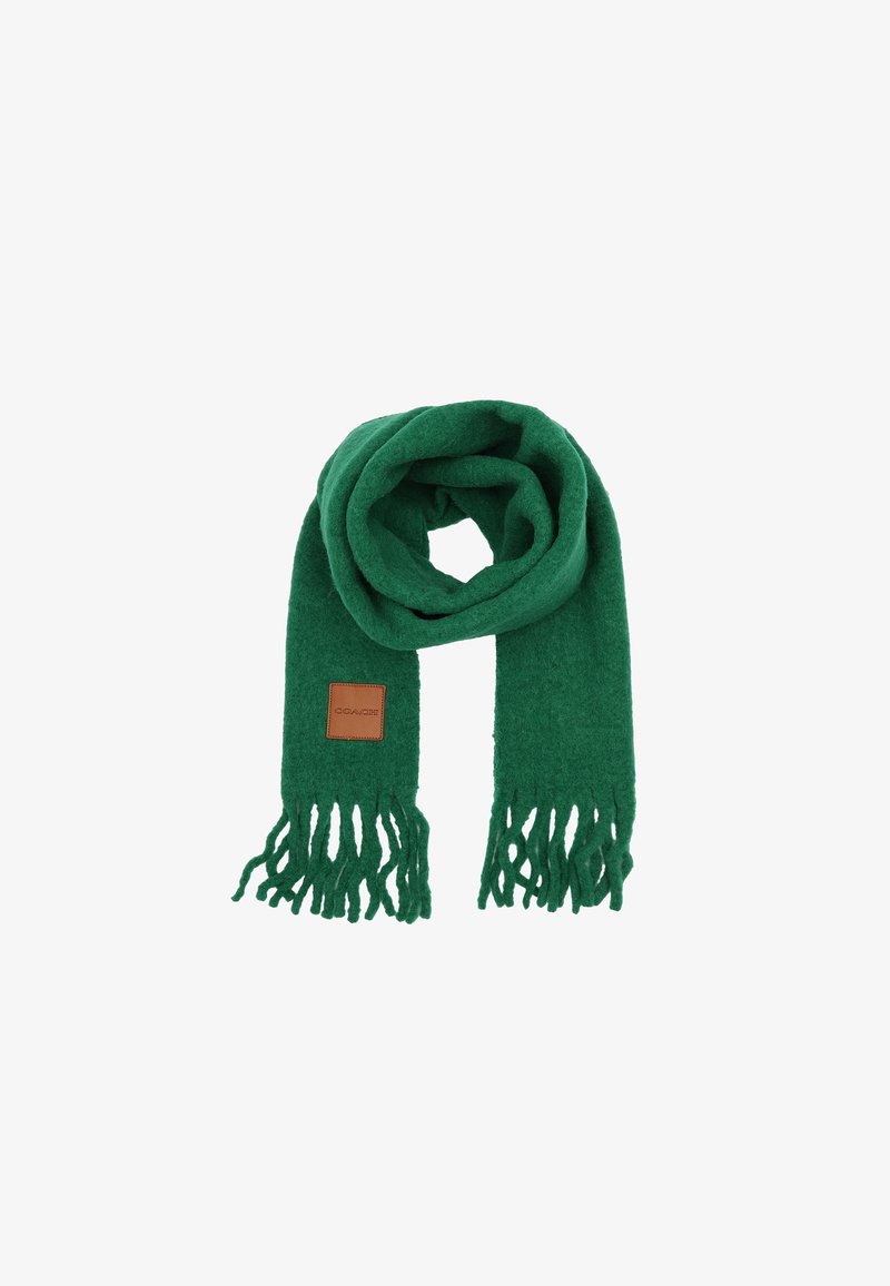 Écharpe en laine verte avec des bords à franges et un écusson de marque en cuir marron, disposée en boucle sur un fond blanc.