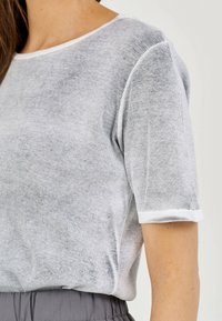 Szaro paskowana koszulka z krótkim rękawem o miękkiej, teksturowanej powierzchni i okrągłym dekolcie, z kontrastowym białym wykończeniem na rękawach i kołnierzyku.