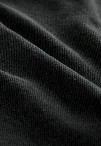 Black fabric features a fine, ribbed texture with subtle sheen and smooth surface, creating gentle folds in the material.
