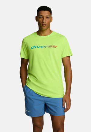 Jasnozielona bawełniana koszulka z krótkim rękawem i okrągłym dekoltem. Posiada logo "diverse" w kolorze niebieskim i brązowym, noszona z niebieskimi szortami.