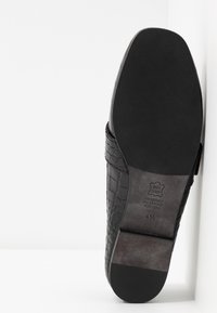 Chaussure en cuir noir avec un motif de crocodile texturé, bout rond et semelle lisse. L'étiquette intérieure indique "tout en cuir" et la taille 4½.