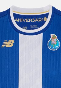 Camisola atlética às riscas azuis e brancas, feita de tecido texturizado. Apresenta um colarinho redondo, um logótipo dourado e o emblema do clube no lado esquerdo do peito.