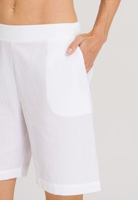Pantaloni corti bianchi a trama tessuta con un motivo a righe testurizzato, vita elastica e tasche laterali. Vestibilità su misura con un design alla lunghezza del ginocchio.