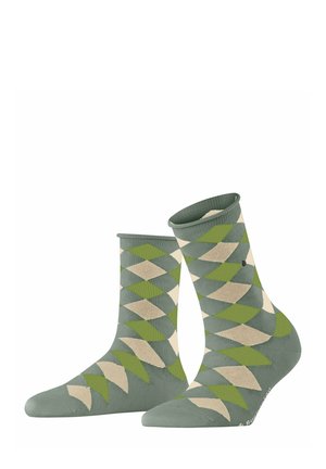 Groene sokken met een diamantpatroon in lichtbeige en variërende tinten groen, rechtopstaand tegen een witte achtergrond.