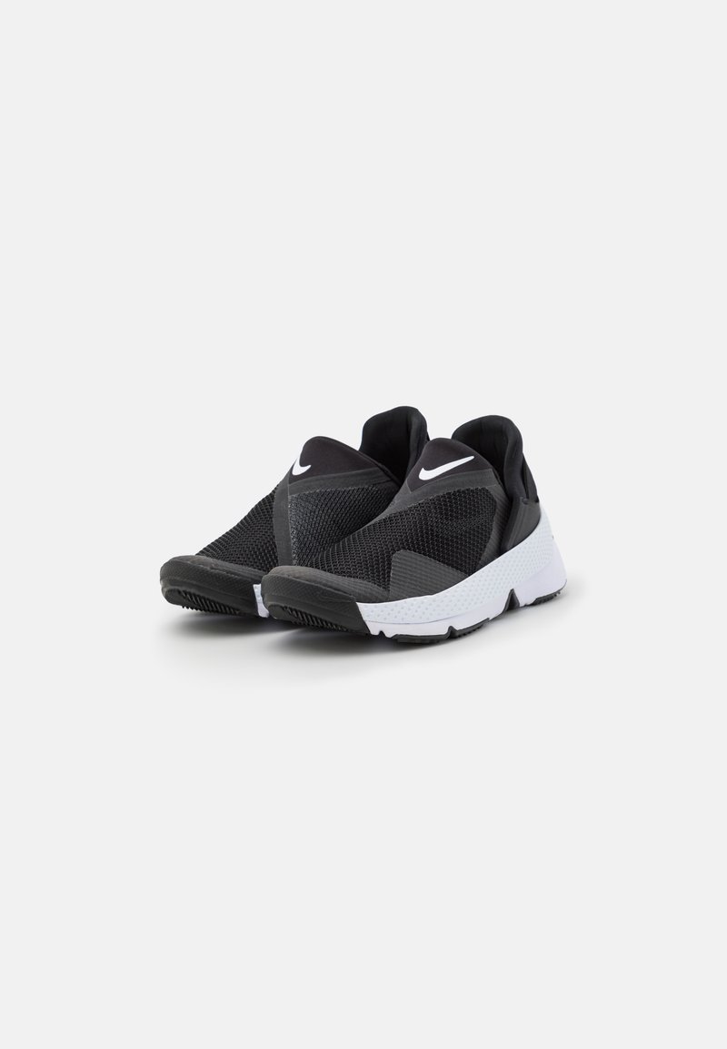 Zapatillas deportivas negras con parte superior de malla texturizada, diseño sin cordones y suela blanca con tracción con patrón. Logotipo icónico en la lengüeta.