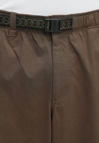 Καφέ σορτς με ελαστική μέση και υφασμένη μαύρη ζώνη με πόρπη. Το ύφασμα φαίνεται λείο με διακριτική υφή και λεπτομέρειες πλευρικής ραφής.