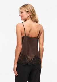 Camisole en satin marron à fines bretelles, avec un ourlet en dentelle noire texturée. Finition lisse avec une coupe légèrement ample.
