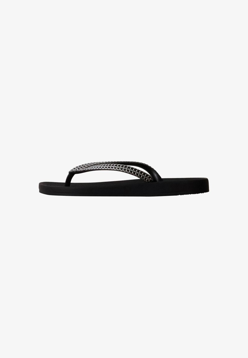 Sandale flip-flop noire avec une semelle plate et une bride texturée ornée de petites perles argentées.