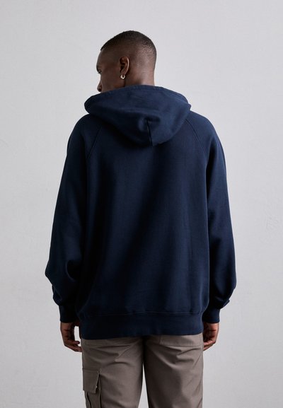 Felpa blu navy con un ampio cappuccio regolabile. Presenta una vestibilità comoda, polsini e orlo a coste. Il materiale sembra morbido e spesso.