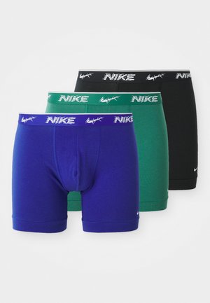 Trzy pary bokserków Nike w kolorach fioletowym, zielonym i czarnym. Każda para ma kontrastującą białą gumkę w pasie z detalami w postaci logo.