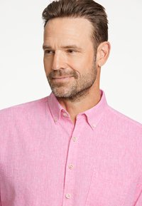 Lichtroze overhemd met knopen, gemaakt van een gestructureerde stof, met een standaardkraag, een borstzak en witte knopen.