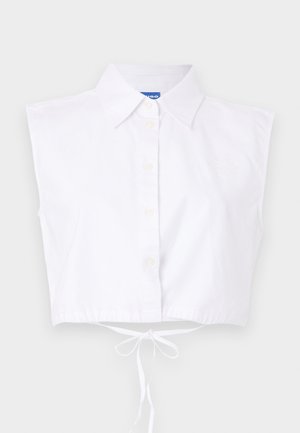 Valkoinen, lyhythihainen, kauluksellinen toppi, jossa on nappisuljenta ja vyötäröllä nauha; etuosassa on hienovarainen brodeerattu logo.