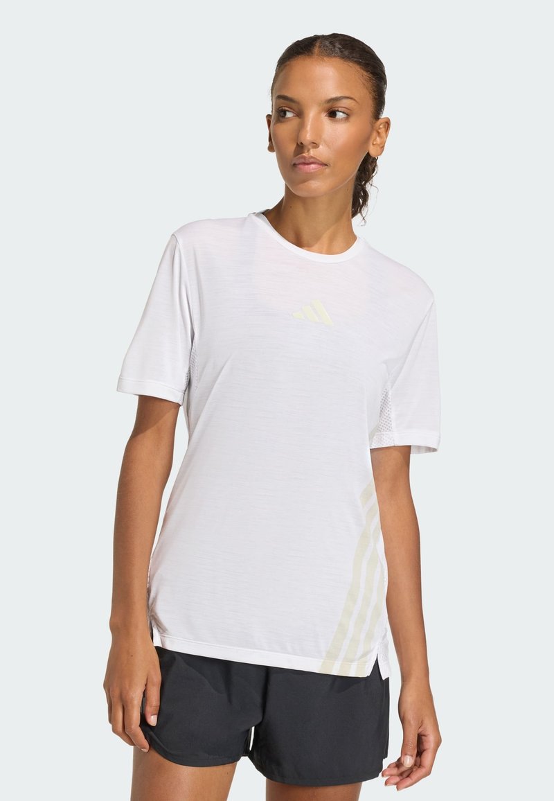 Weißes Sport-T-Shirt mit kurzen Ärmeln, strukturiertem Stoff und dezentem gelbem Drei-Streifen-Design auf der linken Seite. Schwarze Shorts.