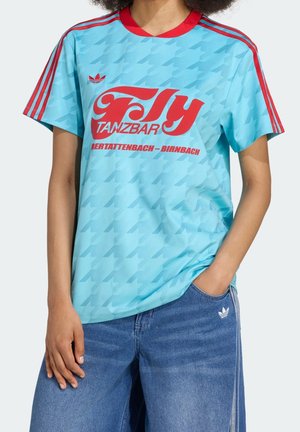 Osoba ubrana w jasnoniebieski t-shirt Adidas z czerwonymi paskami i napisem "Fly Tanzbar Obertattenbach - Birnbach", w połączeniu z niebieskimi dżinsami.