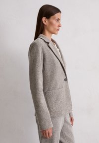Light brown, textured blazer with a single button closure and notched lapels. Features pockets and a tailored fit. Soft fabric.