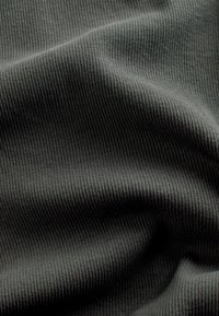 Mörkgrå ribbad tyg med en mjuk yta, präglat av jämnt fördelade vertikala linjer och en slät finish, draperad i mjuka veck.