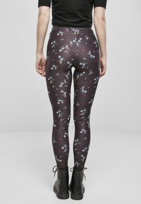 Leggings noirs avec un imprimé floral comportant des accents blancs, bleus et rouges, fabriqués dans un matériau extensible, associés à des bottines noires.