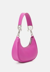 Sac à épaule en cuir rose avec fermeture éclair argentée et sangle détachable, présentant des boucles argentées en forme de visages.