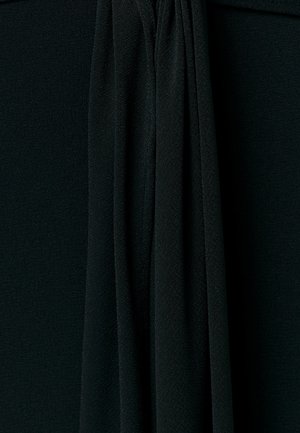 Schwarzer strukturierter Stoff mit vertikalen Falten, die in der Nahaufnahme weiche Schatten und Tiefe erzeugen.