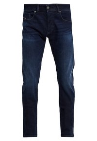 Jeans ajustados de color azul oscuro, fabricados en denim, que cuentan con cinco bolsillos, un cierre de botón y un ligero desgaste en las piernas.