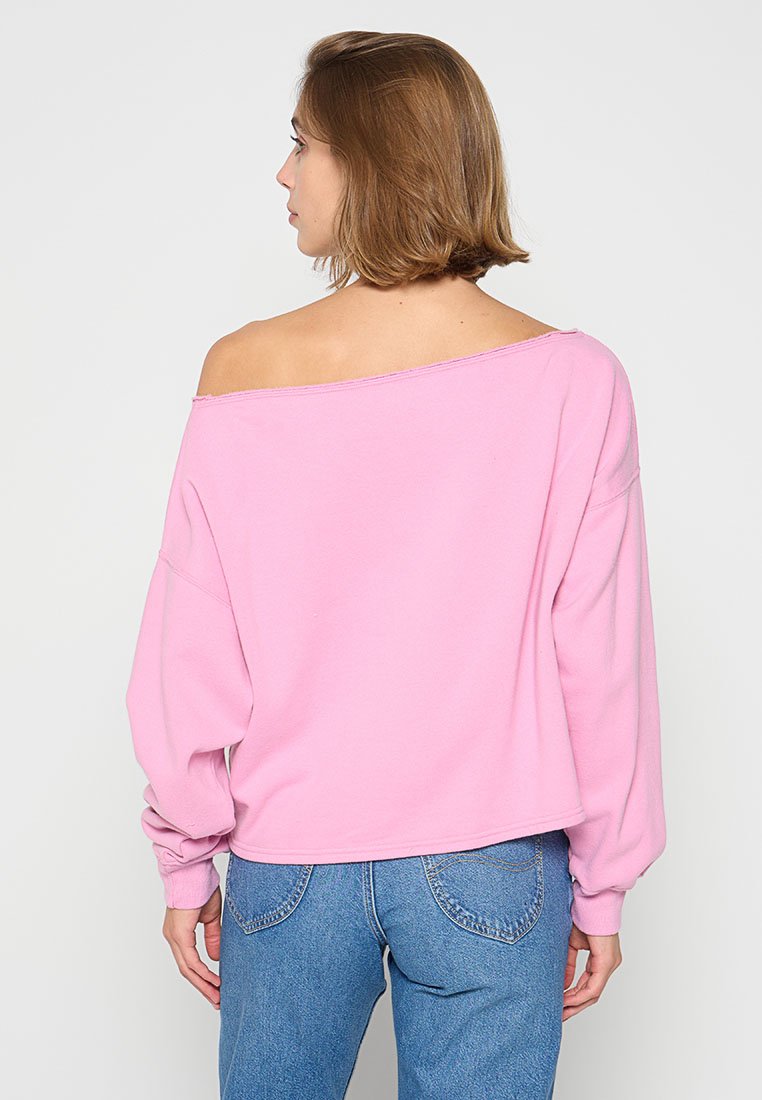 Rosa schulterfreier Sweatshirt mit langen Ärmeln, lockerer Passform und weichem Material. Kombiniert mit hellblauen High-Waist-Jeans.