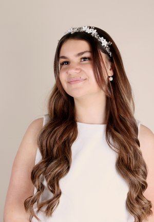 Inserzione di una fascia floreale bianca con accenti argentati indossata da una persona con lunghi capelli castani ondulati, vestita con una canotta bianca senza maniche.