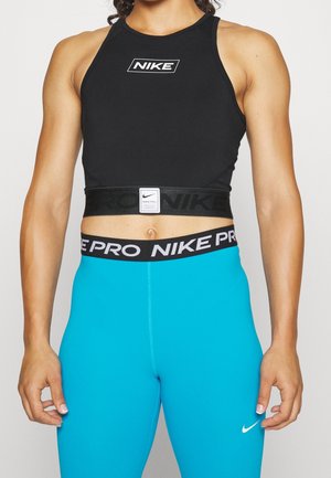 Sort atletisk crop top med en kraftig sort talje, der har et hvidt "Nike Pro" logo og et lille hvidt Nike logo på brystet. Teal leggings.